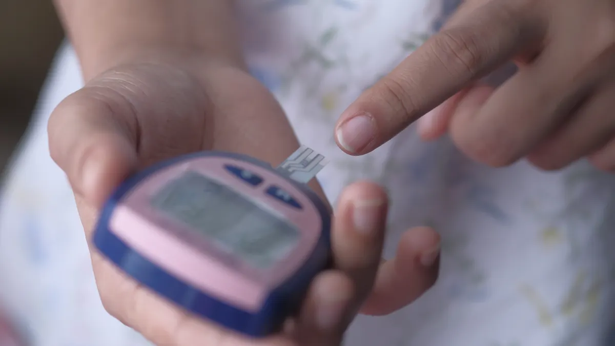 Gestational Diabetes Test Forms: One-Step vs Two-Step Screening Person checking blood sugar with a glucose meter