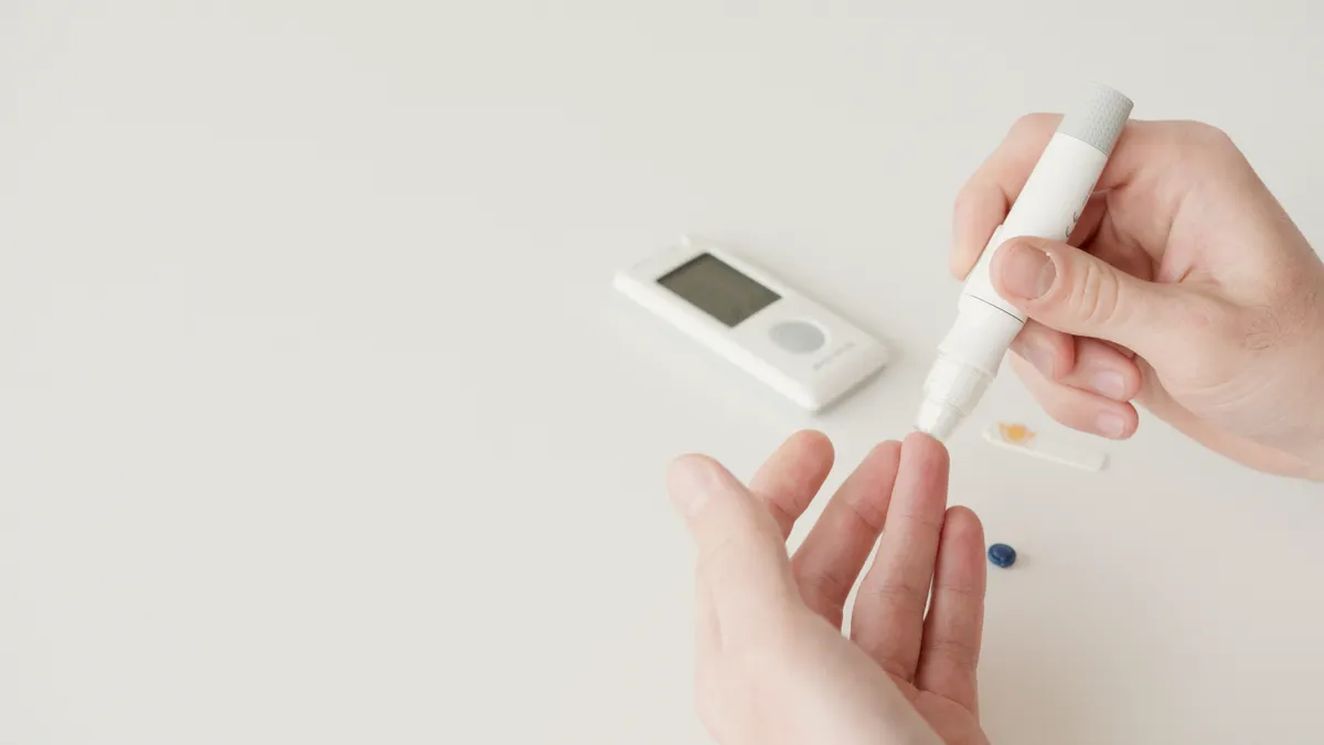 Gestational Diabetes Test Forms: One-Step vs Two-Step Screening Hands doing a finger-prick glucose test with meter nearby