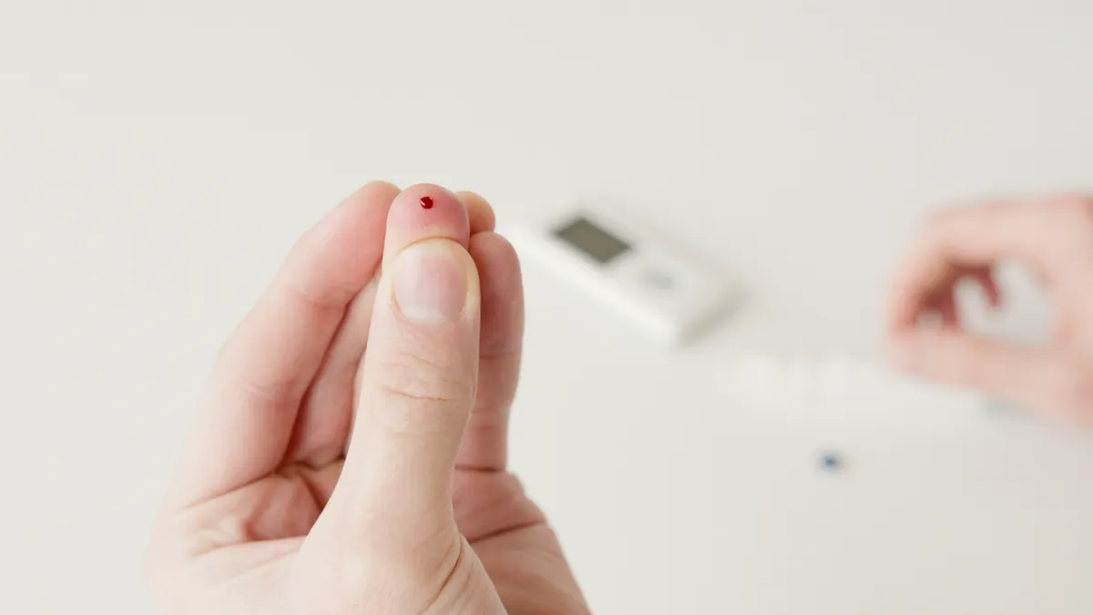 finger prick with blood drop and glucose meter
