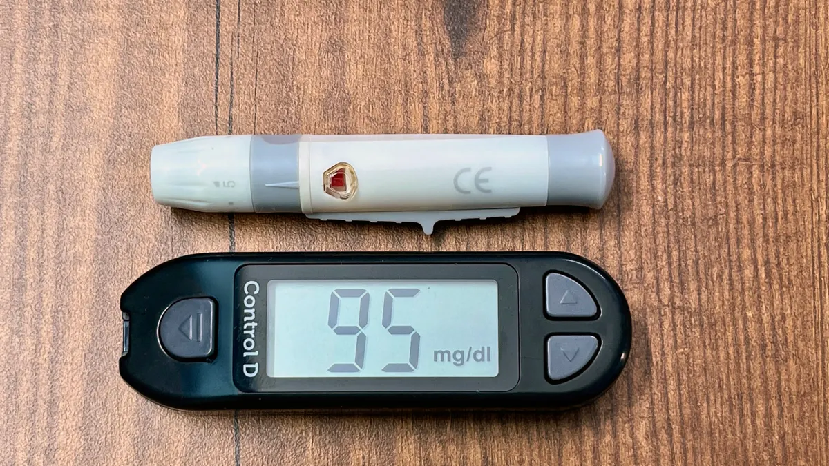 blood glucose meter showing a reading and lancet pen