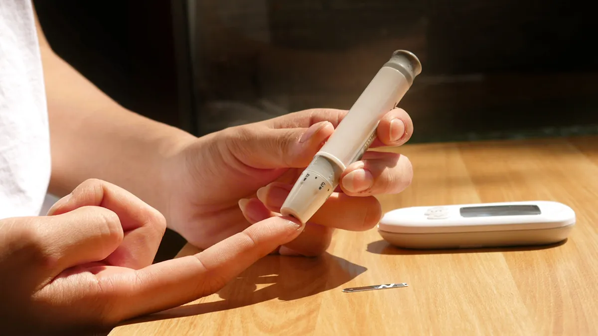 What to Do If Your Blood Sugar Is Too High During Pregnancy — A person is using a digital thermometer to check their blo